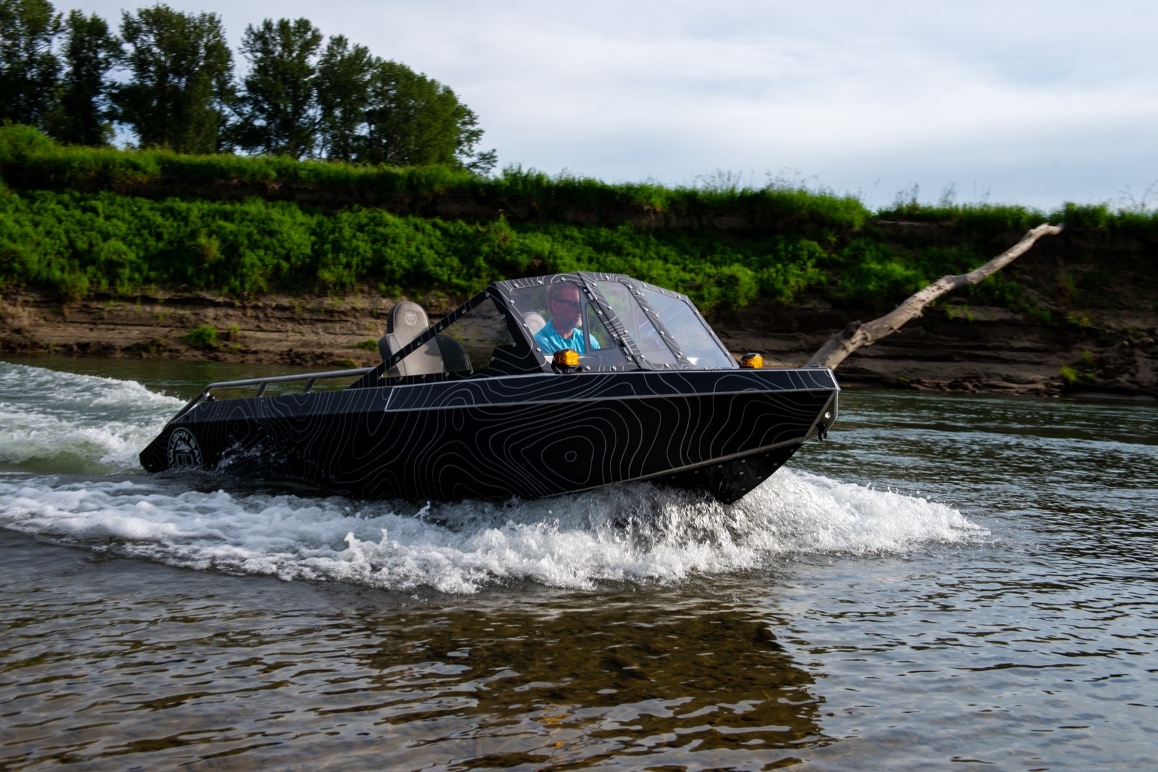 The topo-wrap jet boat carving a hard turn on the river and throwing a wall of spray