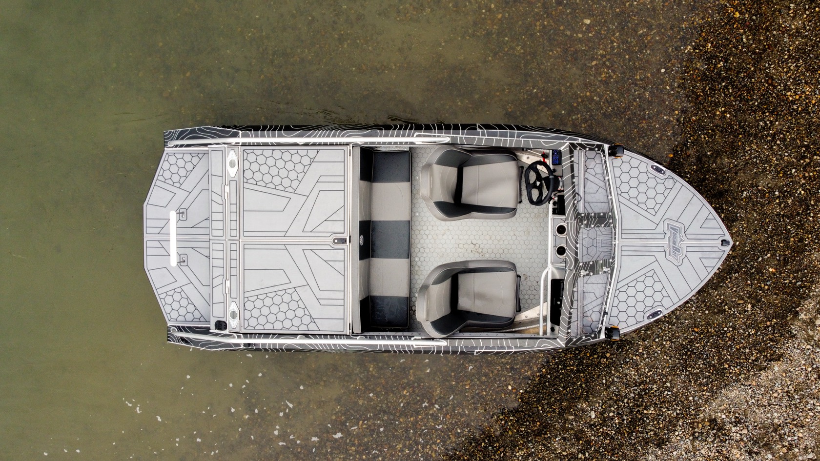 Top-down aerial view of the topo-wrap jet boat floating in the shallows along the riverbank