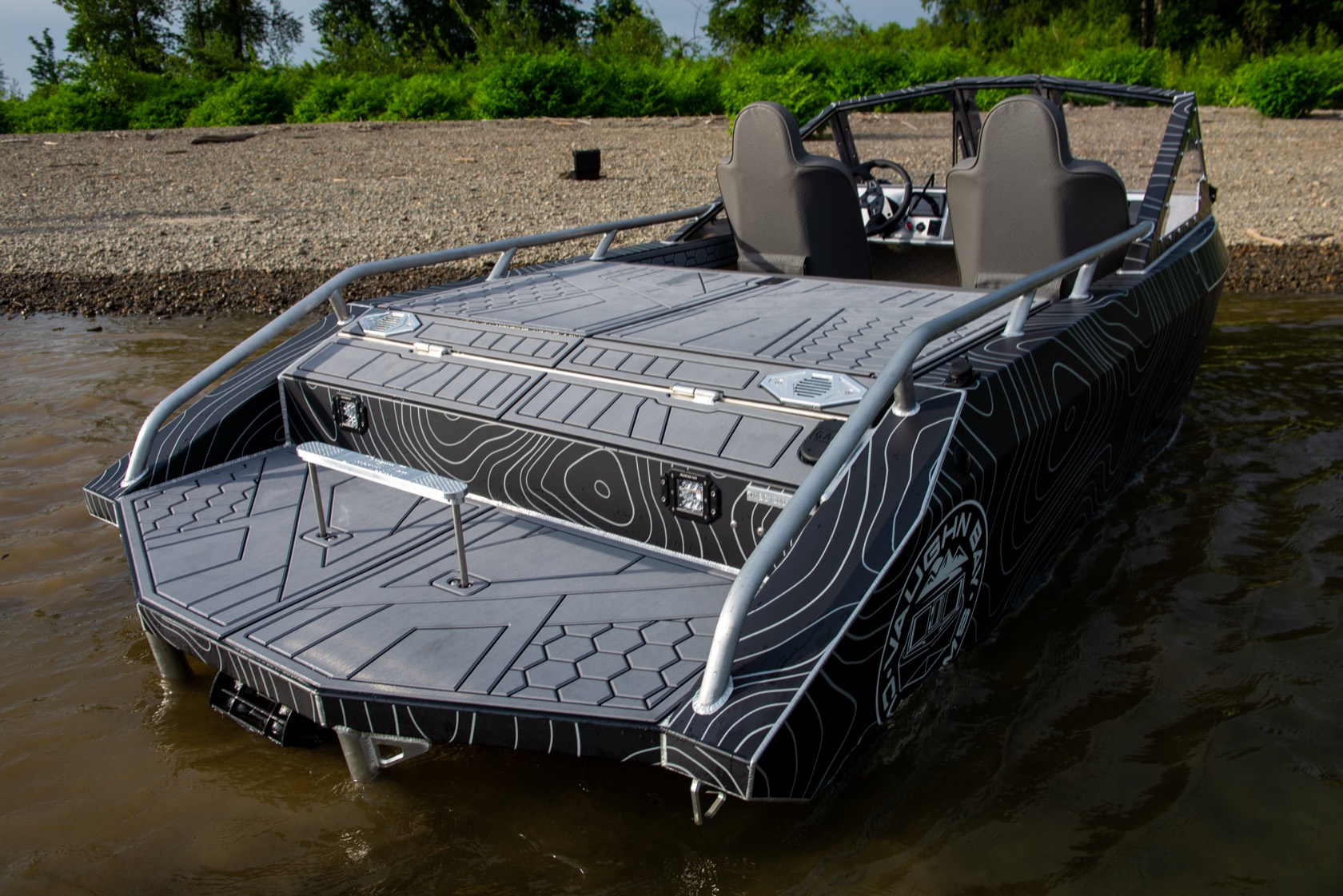 Rear-quarter view of the jet boat showing the open rear deck, storage hatches and wrap-around rail