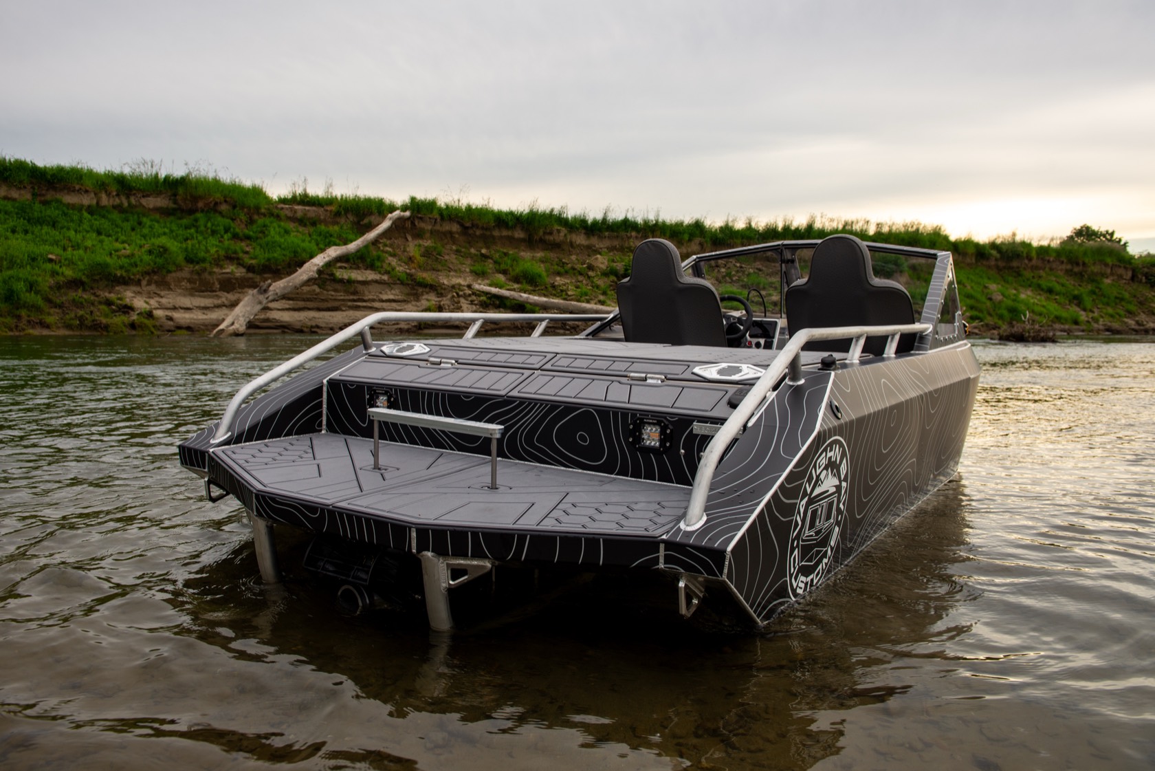 Stern-quarter view of the jet boat on the river at dusk with the open rear deck and seats