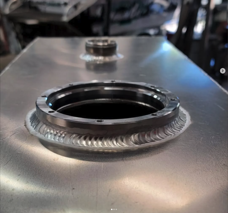 Close-up of stacked aluminum TIG weld beads around a circular pump fitting flange