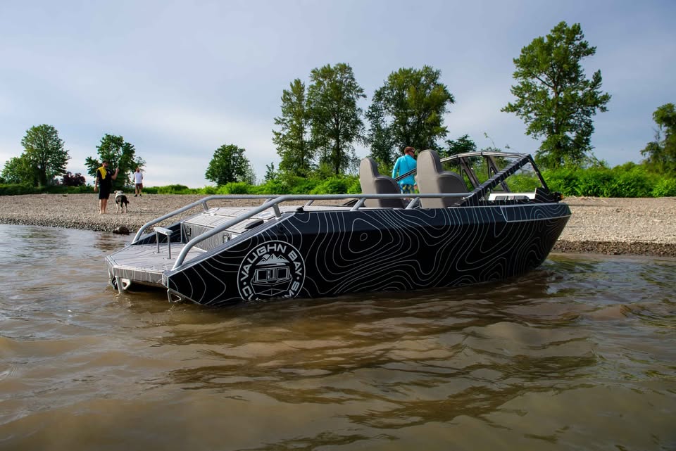 Port-side profile of the VB12 show boat on a river bar, mountain logo on the hull side