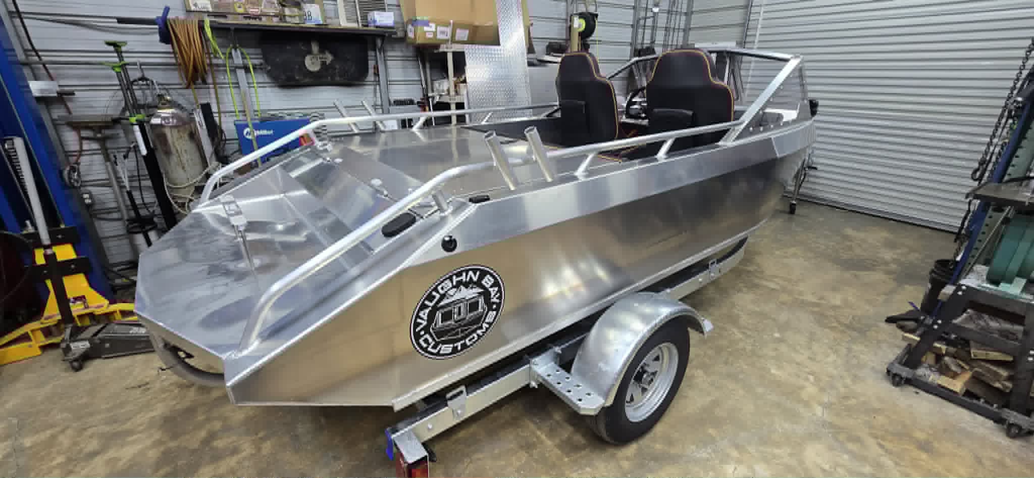 Bare welded aluminum VB14 hull on its trailer in the shop before finishing